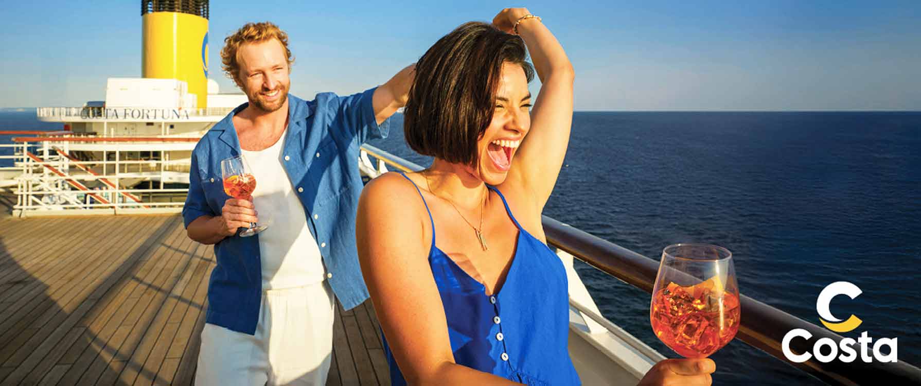 Mężczyzna i kobieta w promieniach słońca na pokładzie statku trzymająca w rękach kieliszek z drinkiem